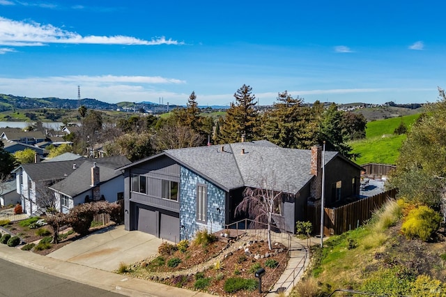 view of front of house featuring a garage, driveway, a shingled roof, and fence