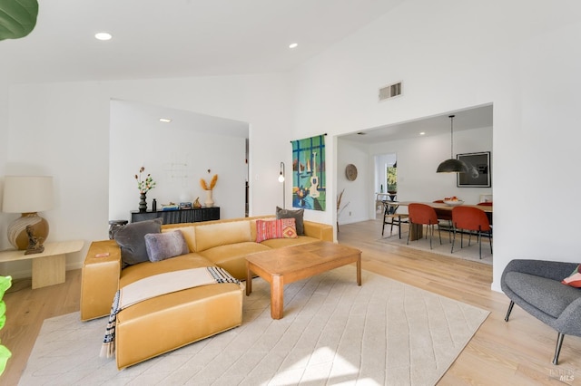 living room featuring light wood-style floors, visible vents, high vaulted ceiling, and recessed lighting