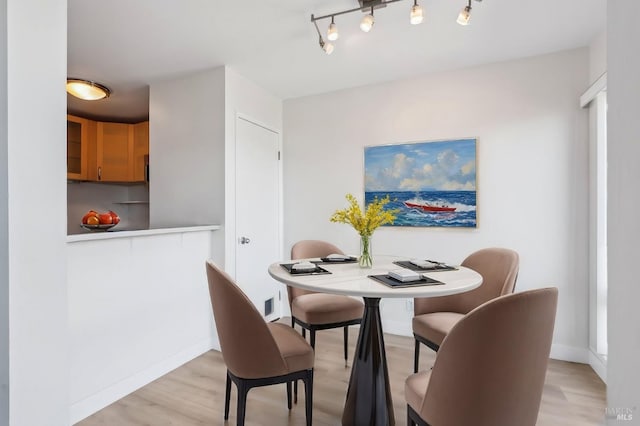 dining space featuring light wood finished floors, baseboards, and track lighting