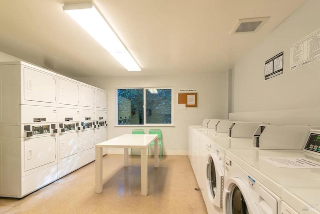 community laundry room featuring washer and dryer, stacked washer and clothes dryer, visible vents, and baseboards