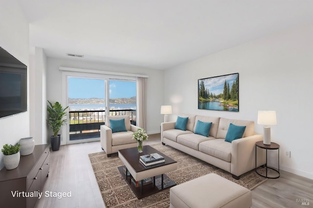 living area featuring light wood-type flooring, visible vents, and baseboards