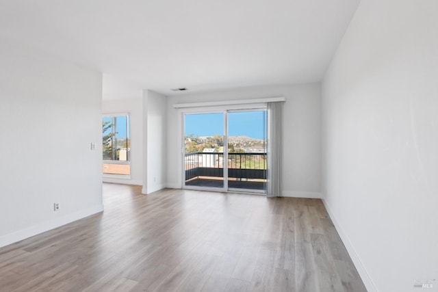 spare room featuring baseboards, visible vents, and wood finished floors