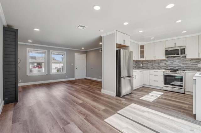 kitchen with stainless steel appliances, visible vents, ornamental molding, and decorative backsplash