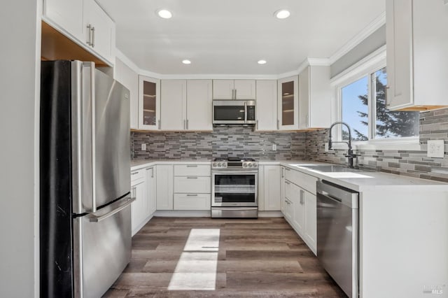 kitchen featuring a sink, wood finished floors, stainless steel appliances, light countertops, and decorative backsplash