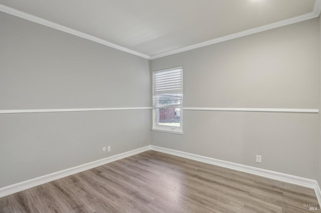 spare room featuring baseboards, wood finished floors, and crown molding