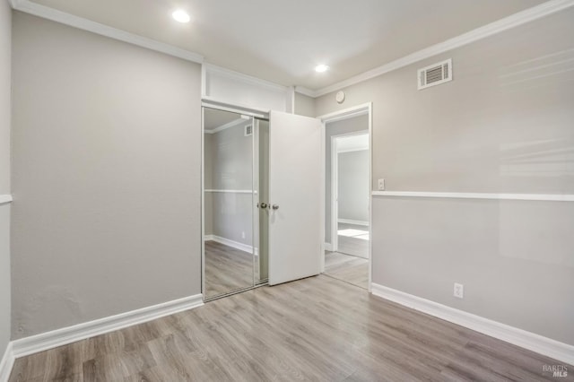 unfurnished bedroom with visible vents, ornamental molding, wood finished floors, recessed lighting, and baseboards