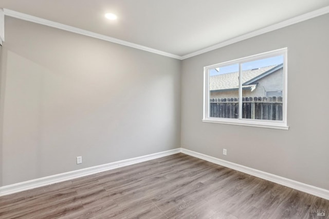 spare room with crown molding, baseboards, and wood finished floors