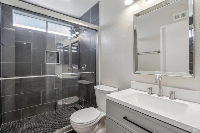 bathroom with visible vents, toilet, a stall shower, a textured wall, and vanity