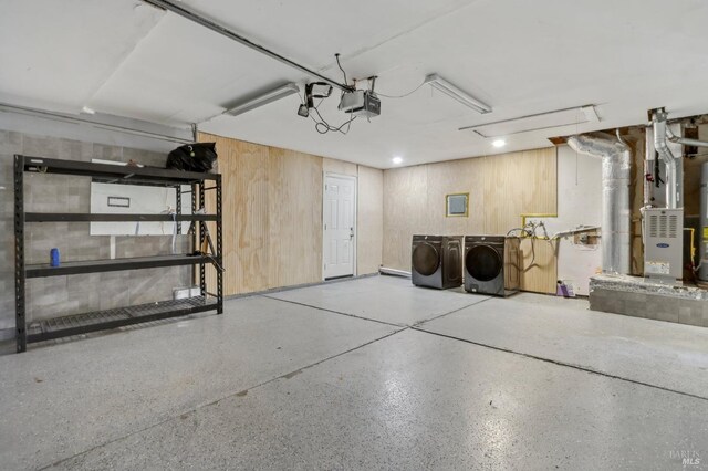 garage with washer and dryer, heating unit, a garage door opener, and wood walls