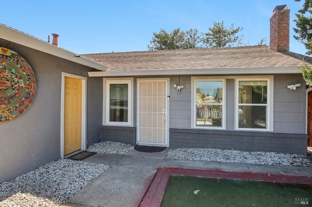 property entrance with a chimney and a shingled roof