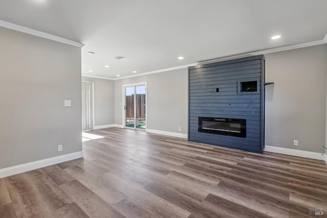 unfurnished living room with wood finished floors, baseboards, and a large fireplace