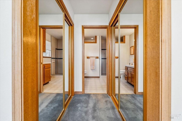 hall featuring baseboards, carpet flooring, and tile patterned floors