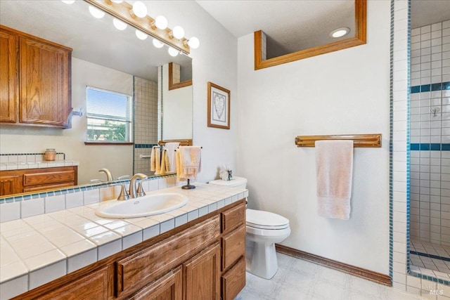 full bath with baseboards, toilet, tile patterned floors, a tile shower, and vanity