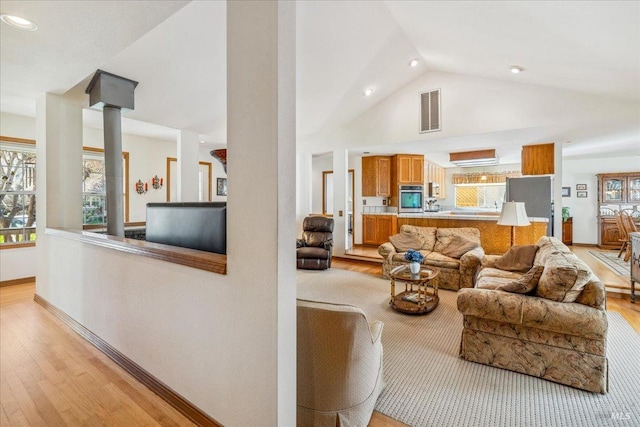 living area with light wood-style floors, baseboards, visible vents, and a wealth of natural light