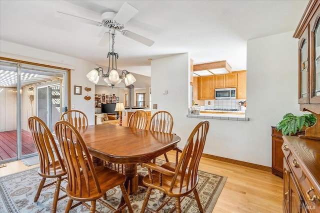 dining space featuring ceiling fan with notable chandelier and light wood-type flooring