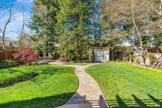 view of yard featuring an outbuilding, a patio area, a fenced backyard, and a storage unit