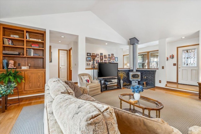 living room with high vaulted ceiling, recessed lighting, a wood stove, and light wood-style flooring