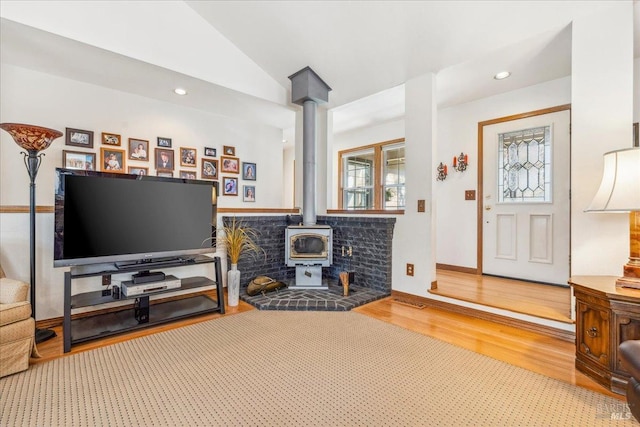 living area featuring vaulted ceiling, wood finished floors, a wood stove, and recessed lighting