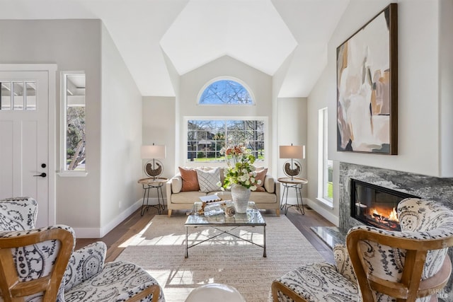 living area featuring vaulted ceiling, a premium fireplace, wood finished floors, and baseboards