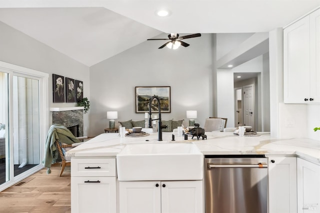 kitchen with dishwasher, open floor plan, light stone countertops, a sink, and a high end fireplace