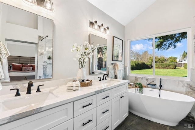 bathroom with double vanity, a freestanding bath, vaulted ceiling, and a sink