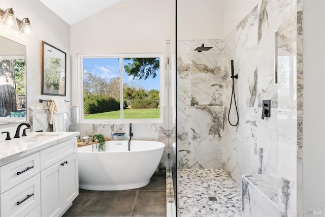 full bathroom with lofted ceiling, vanity, tile walls, a freestanding bath, and a marble finish shower