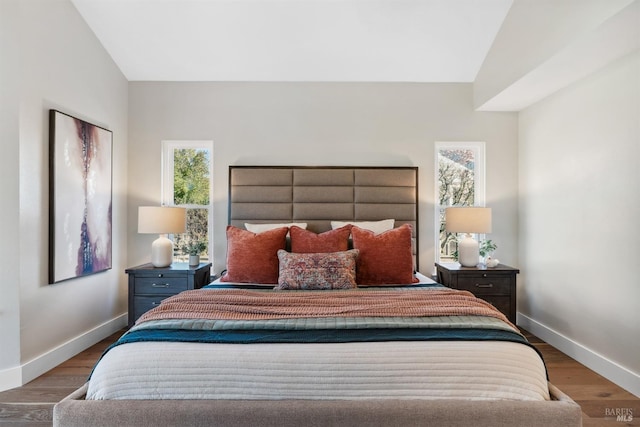 bedroom with vaulted ceiling, wood finished floors, and baseboards