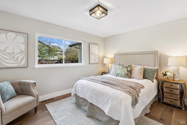 bedroom featuring visible vents, baseboards, and wood finished floors