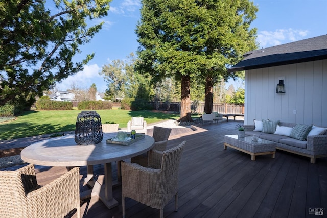 wooden deck featuring outdoor dining space, a lawn, outdoor lounge area, and fence