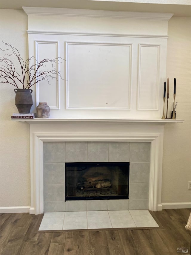 room details featuring a fireplace, baseboards, and wood finished floors