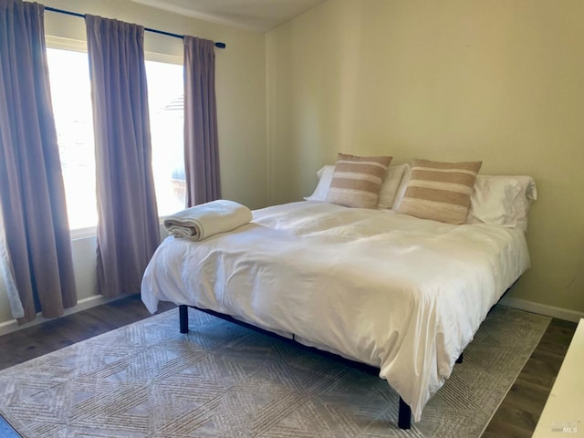 bedroom with multiple windows, baseboards, and wood finished floors