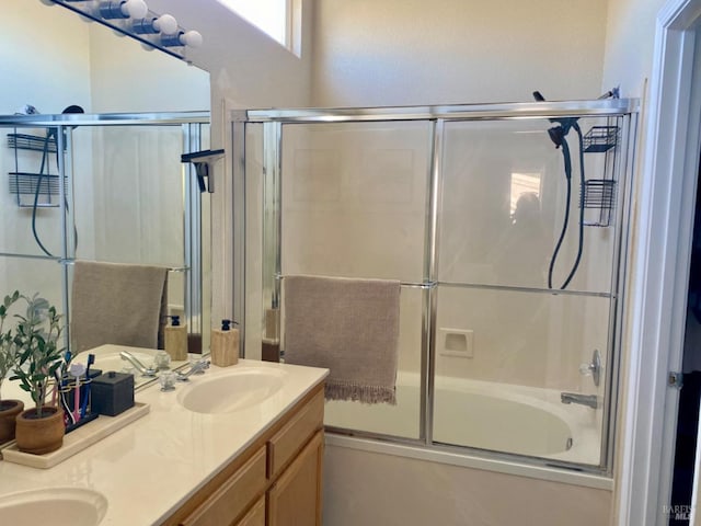 bathroom with double vanity, shower / bath combination with glass door, and a sink