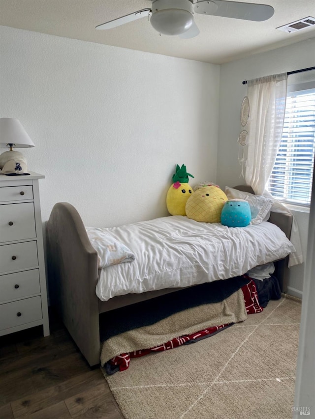 bedroom with a ceiling fan, visible vents, and wood finished floors