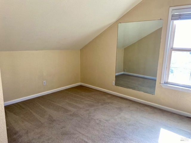 bonus room featuring baseboards, carpet, lofted ceiling, and a healthy amount of sunlight