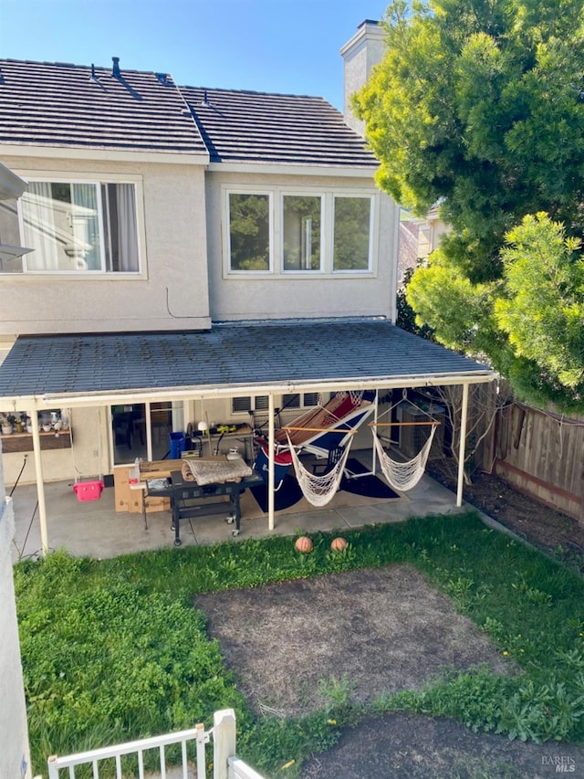 exterior space featuring a patio area, fence private yard, a tile roof, and stucco siding