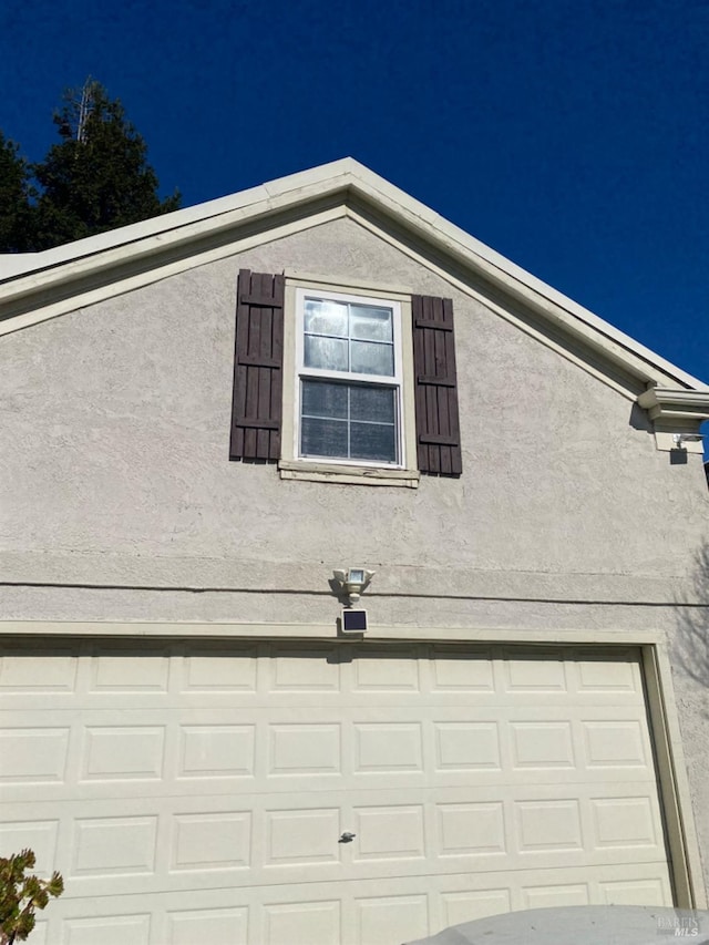 view of side of home with an attached garage and stucco siding