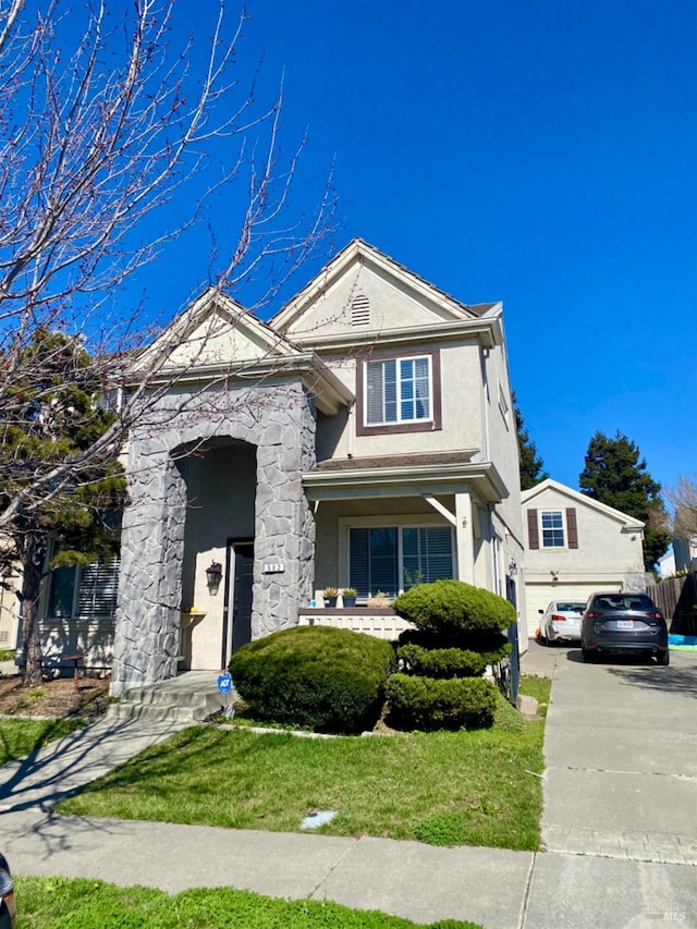 traditional home with driveway, a garage, stone siding, fence, and stucco siding