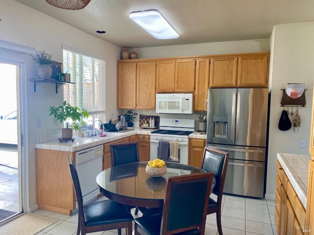 kitchen featuring tile counters, white appliances, and a sink