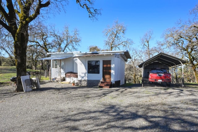 view of outbuilding with entry steps, an outbuilding, fence, and a detached carport