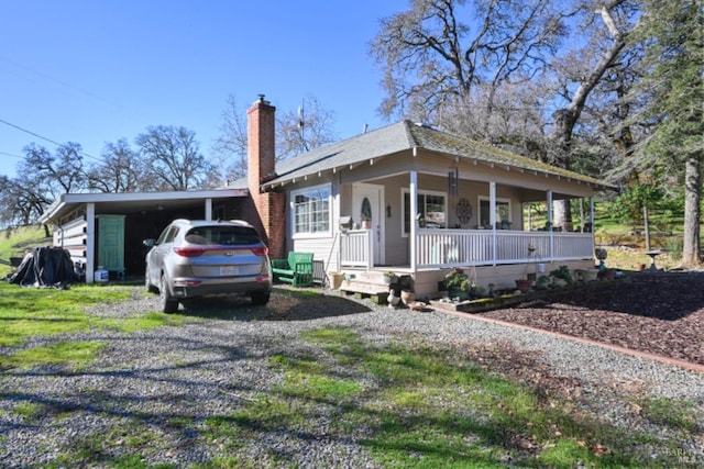 view of front of property featuring an attached carport, covered porch, driveway, and a chimney