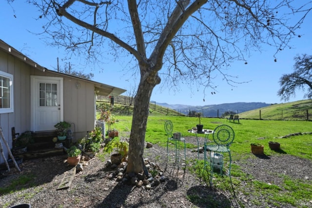 view of yard featuring entry steps, fence, a mountain view, and a rural view