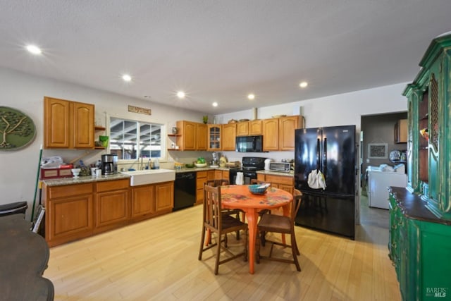 kitchen featuring open shelves, a sink, light wood-style floors, black appliances, and brown cabinetry