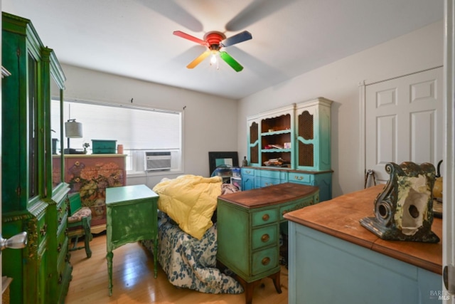 bedroom featuring light wood-type flooring, a ceiling fan, and cooling unit