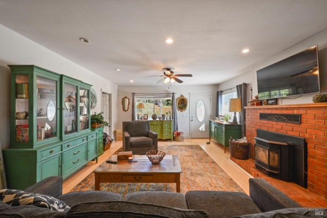 living area with a wood stove, light wood-style flooring, ceiling fan, and recessed lighting