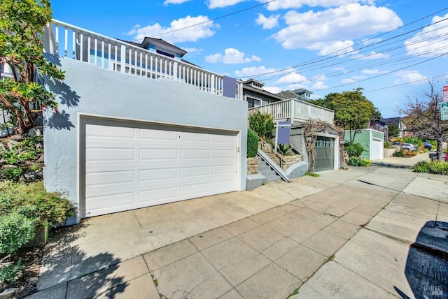 view of front of house featuring a garage, driveway, a balcony, and stucco siding