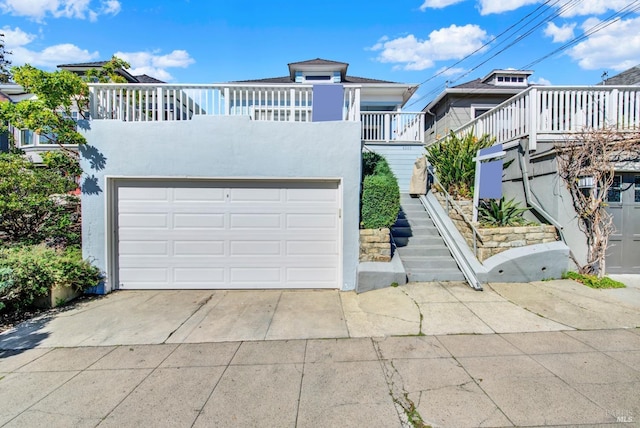 front facade featuring driveway, an attached garage, stairway, and stucco siding