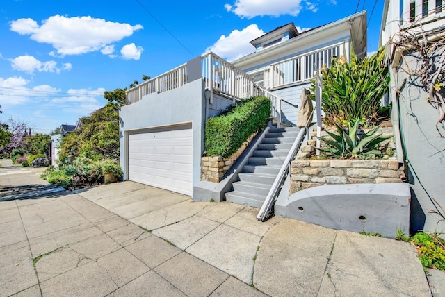 view of home's exterior with concrete driveway, stairway, and stucco siding