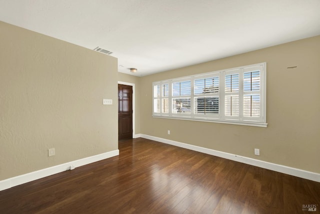 spare room featuring visible vents, baseboards, and wood finished floors