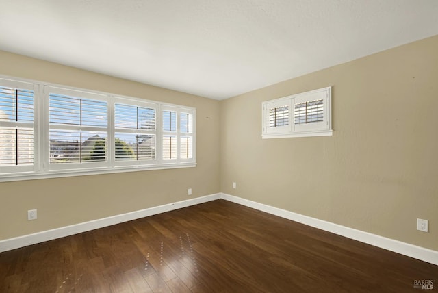 unfurnished room with dark wood-style floors and baseboards