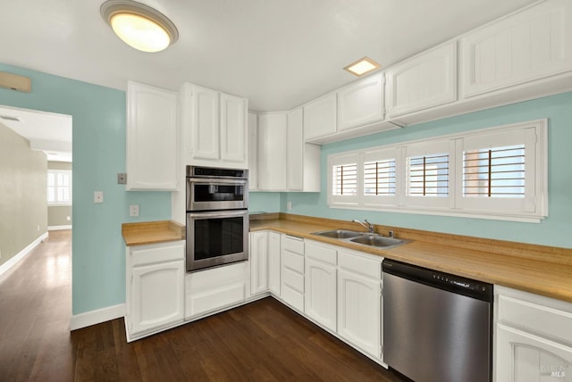 kitchen featuring white cabinets, dark wood finished floors, stainless steel appliances, light countertops, and a sink